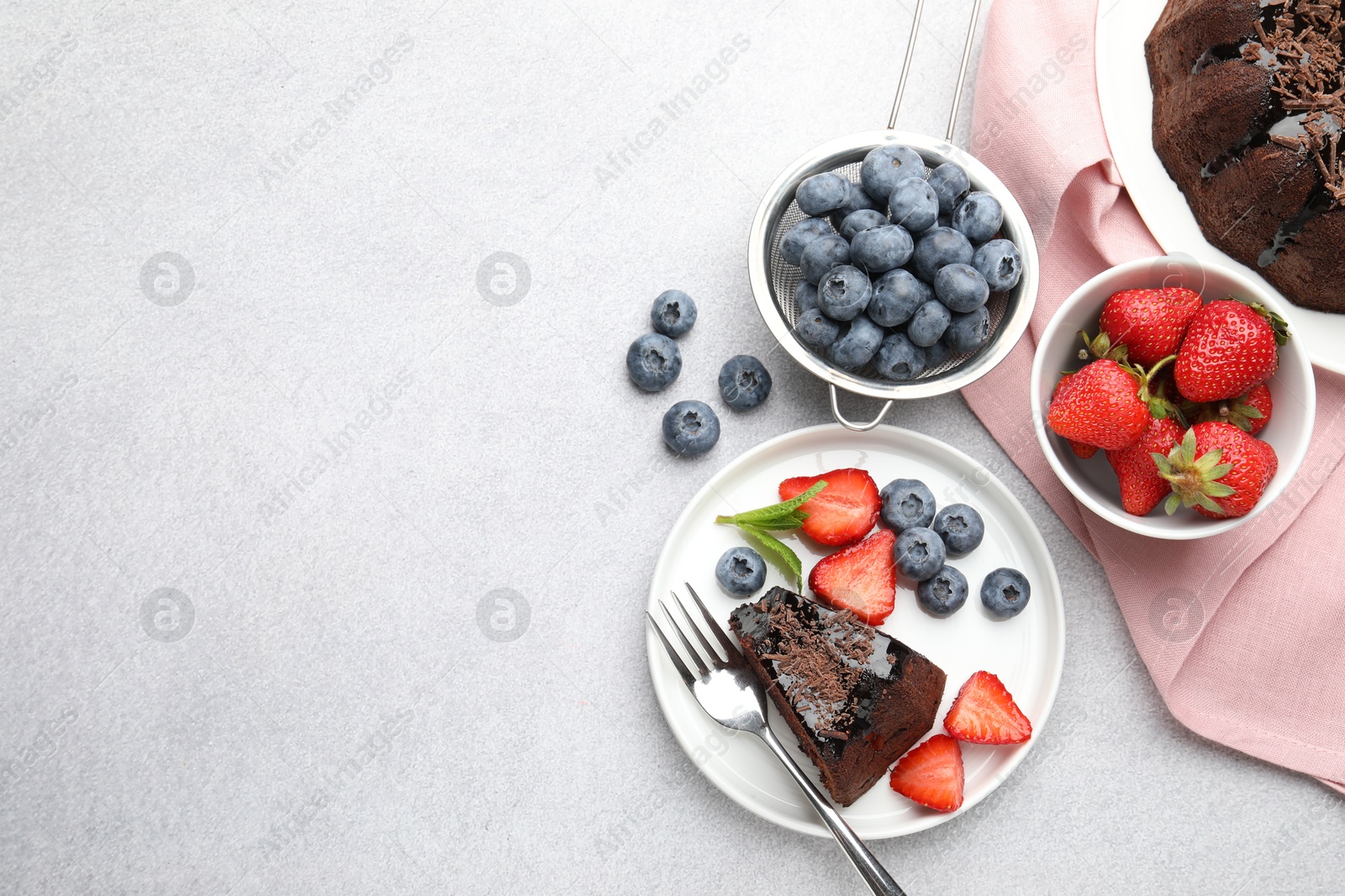 Delicious chocolate bundt cake with strawberries and blueberries on light grey textured table, flat lay. Space for text Photo of Delicious chocolate bundt cake with strawberries and blueberries on light grey textured table, flat lay. Space for text