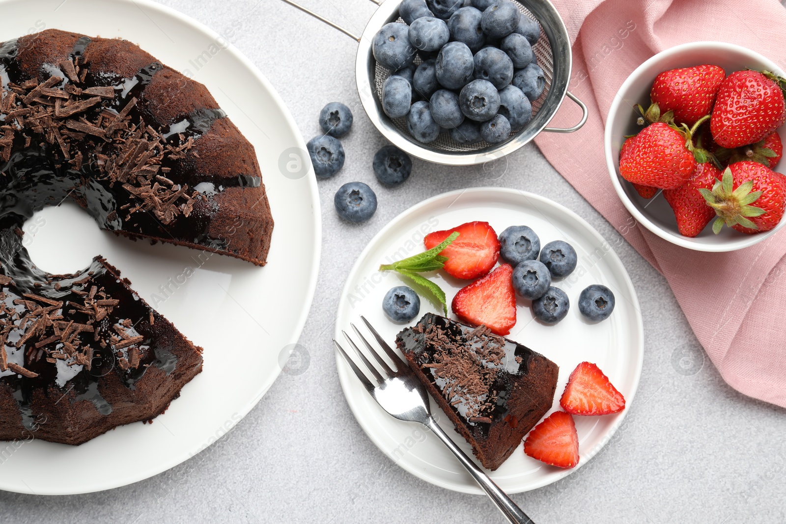Delicious chocolate bundt cake with strawberries and blueberries on light grey textured table, flat lay Photo of Delicious chocolate bundt cake with strawberries and blueberries on light grey textured table, flat lay