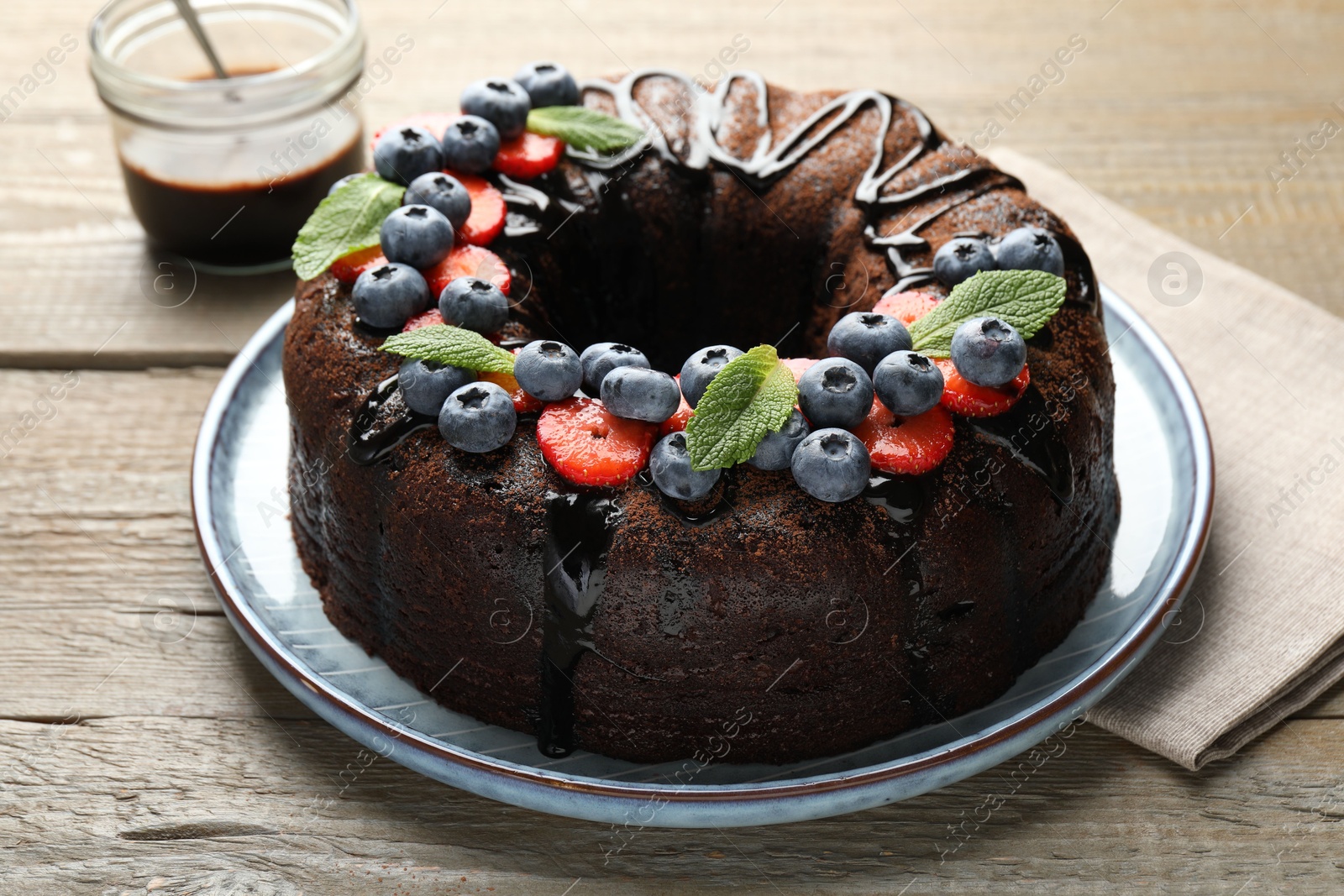 Delicious chocolate bundt cake with strawberries, mint and blueberries on wooden table, closeup Photo of Delicious chocolate bundt cake with strawberries, mint and blueberries on wooden table, closeup