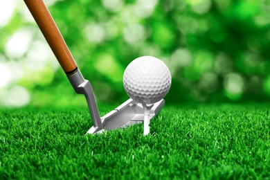 Image of Golf ball on green grass and club outdoors, closeup
