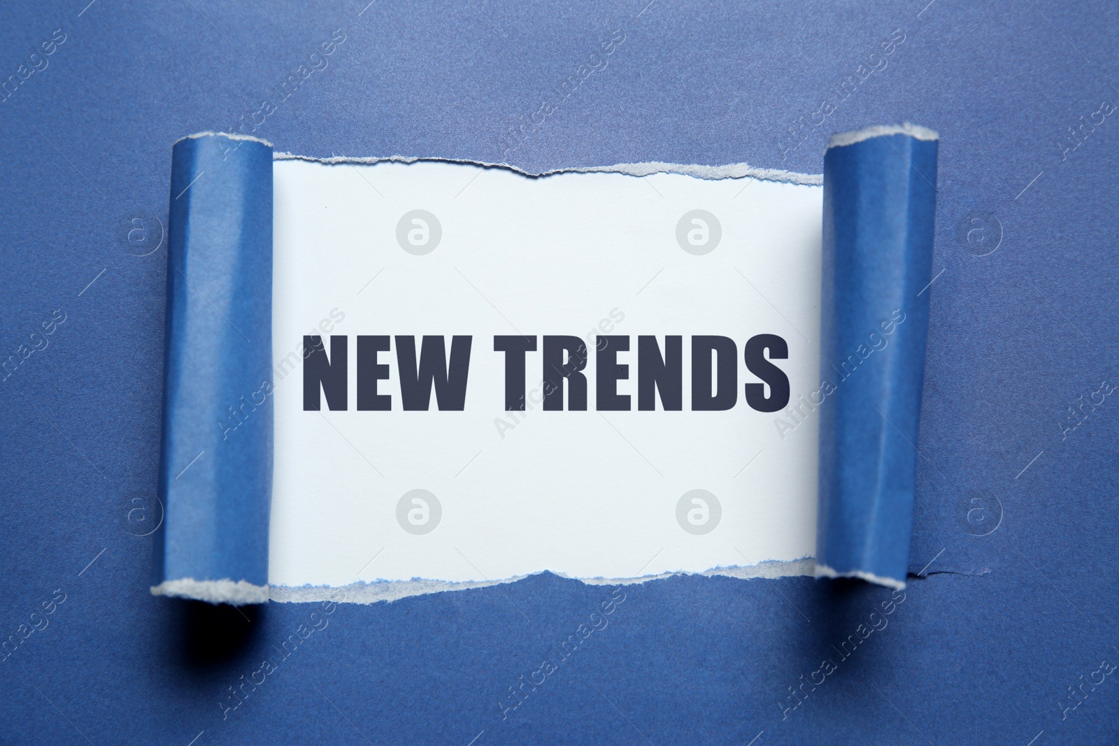 New Trends. Words on white background, through hole in blue paper Image of New Trends. Words on white background, through hole in blue paper