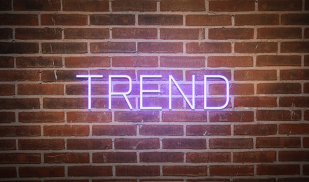 Image of Neon sign with word Trend on brick wall