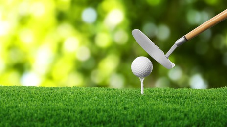 Image of Golf ball on green grass and club outdoors, closeup