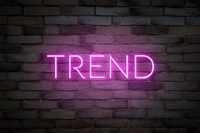 Image of Neon sign with word Trend on brick wall