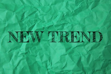 Image of New Trend. Words on crumpled green sheet of paper