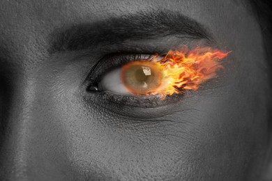 Image of Woman with fire burning in her eye, closeup. Black and white effect