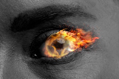 Image of Woman with fire burning in her eye, closeup. Black and white effect