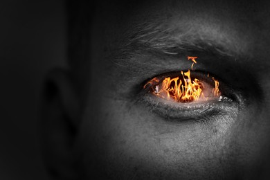 Image of Man with fire burning in his eye, closeup. Black and white effect