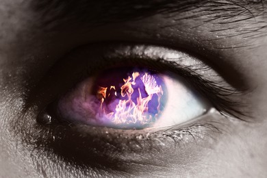 Image of Man with fire burning in his eye, closeup. Black and white effect