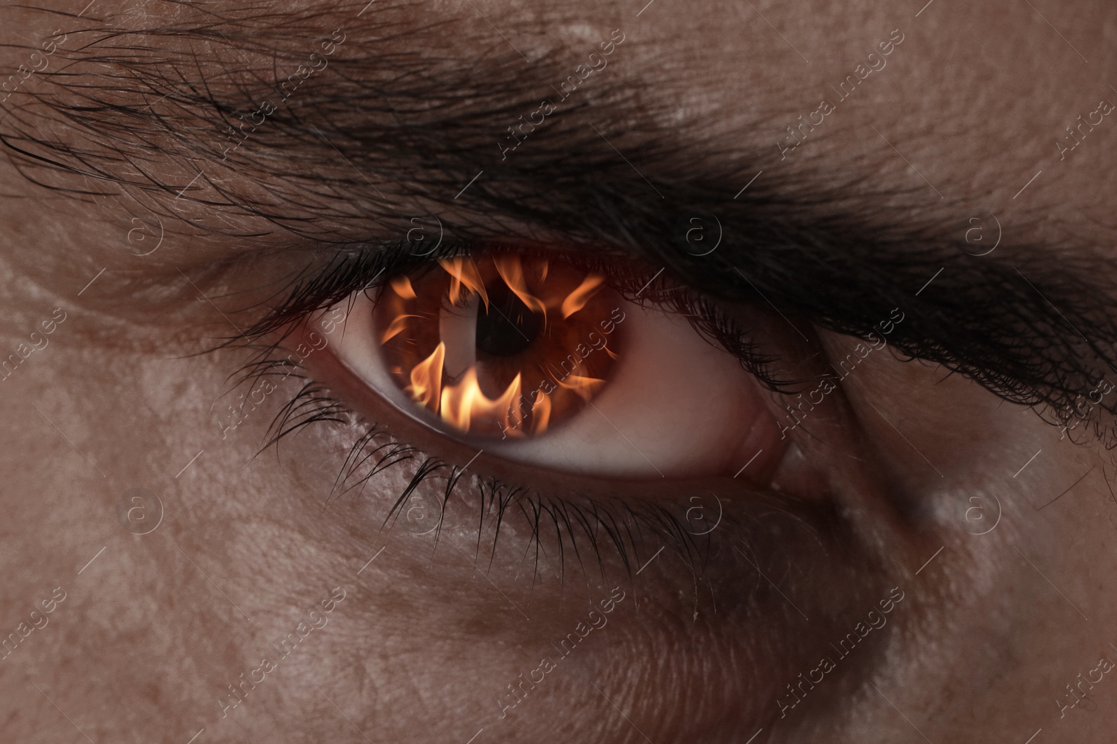 Man with fire burning in his eye, closeup Image of Man with fire burning in his eye, closeup