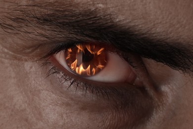 Image of Man with fire burning in his eye, closeup