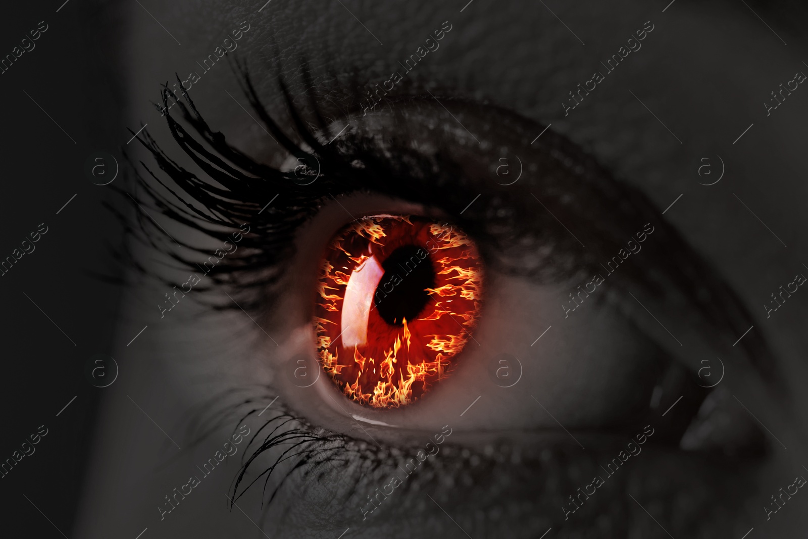 Image of Woman with fire burning in her eye, closeup. Black and white effect