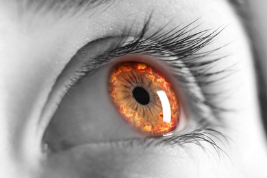 Image of Woman with fire burning in her eye, closeup. Black and white effect