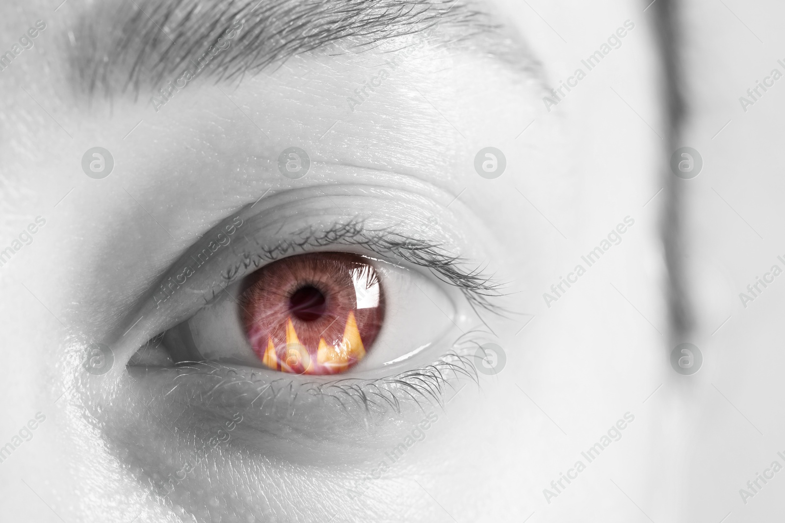 Image of Woman with fire burning in her eye, closeup. Black and white effect