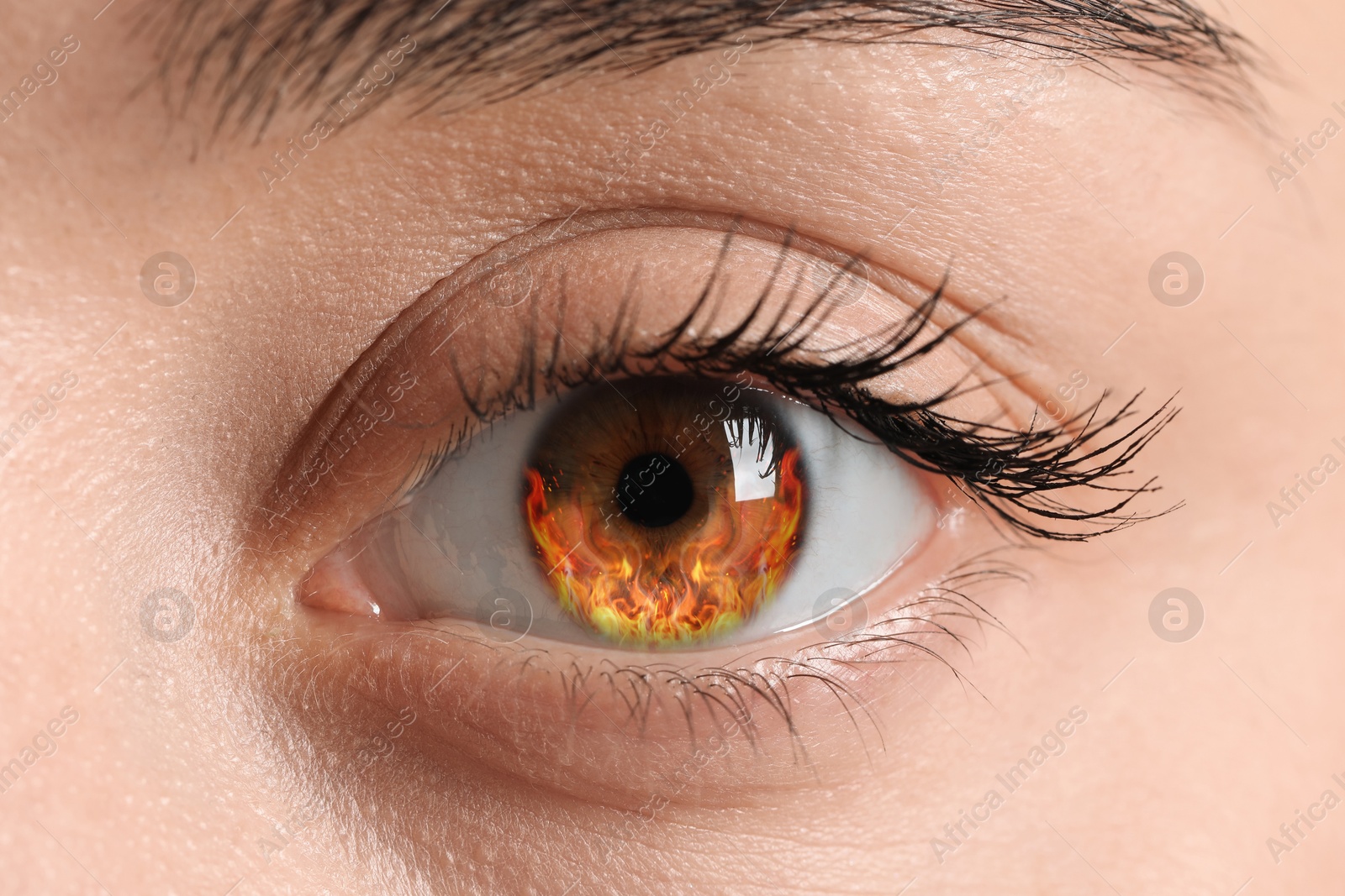 Image of Woman with fire burning in her eye, closeup