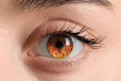 Image of Woman with fire burning in her eye, closeup