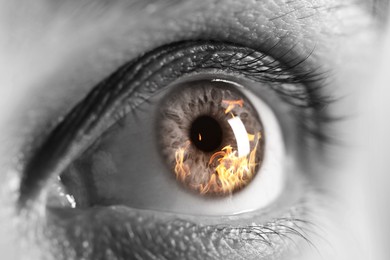 Image of Woman with fire burning in her eye, closeup. Black and white effect