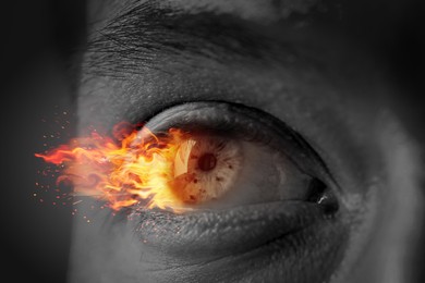 Image of Man with fire burning in his eye, closeup. Black and white effect