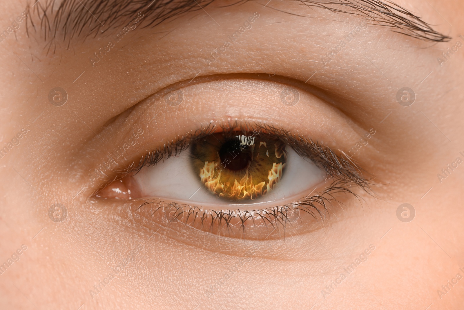 Woman with fire burning in her eye, closeup Image of Woman with fire burning in her eye, closeup
