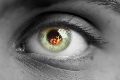Image of Woman with fire burning in her eye, closeup. Black and white effect