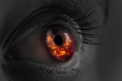 Image of Woman with fire burning in her eye, closeup. Black and white effect