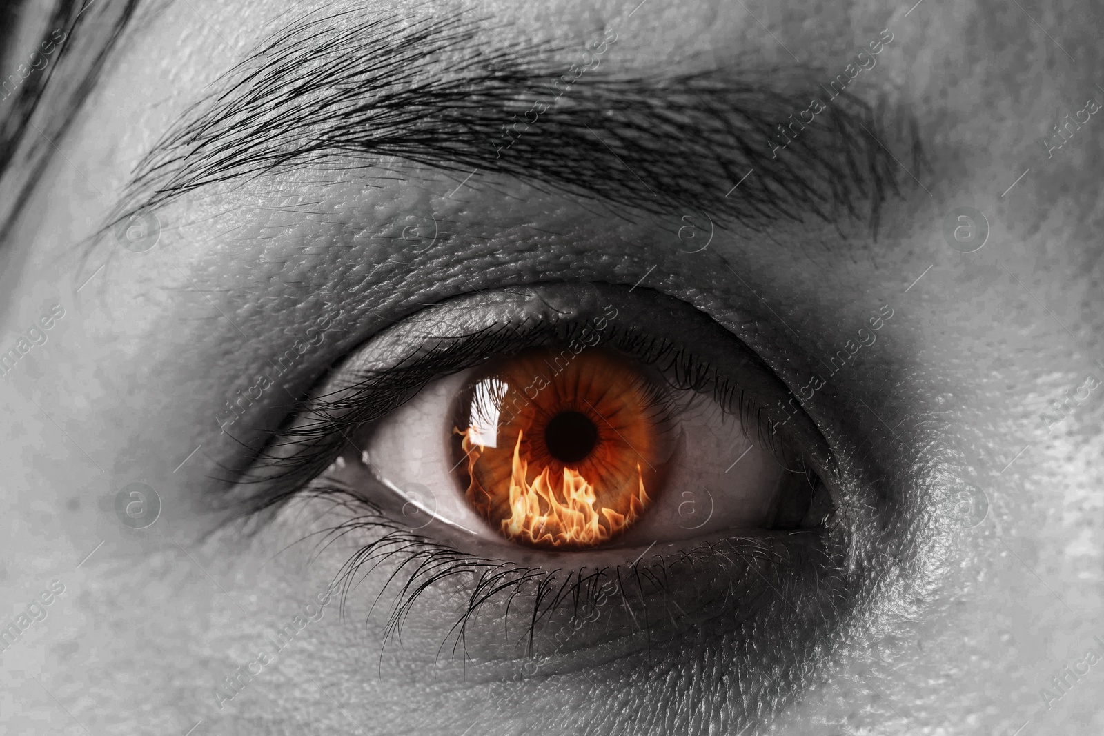Woman with fire burning in her eye, closeup. Black and white effect Image of Woman with fire burning in her eye, closeup. Black and white effect