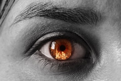 Image of Woman with fire burning in her eye, closeup. Black and white effect