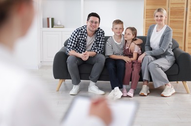 Photo of Happy family having consultation with psychologist in office, selective focus