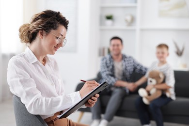 Photo of Father and son having consultation with psychologist in office, selective focus