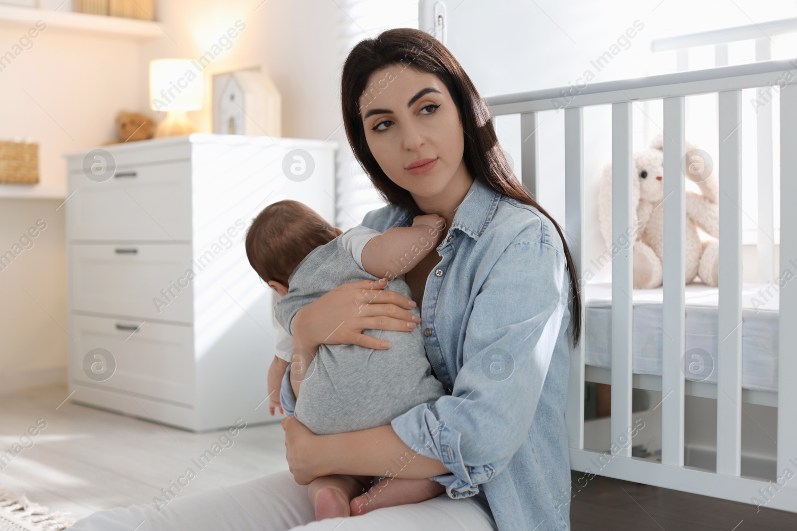 Photo of Woman suffering from postpartum depression with her little baby at home