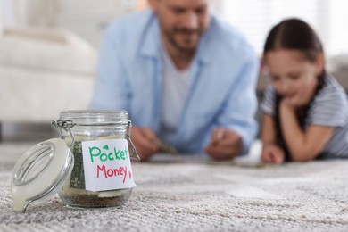 Photo of Jar with pocket money, father and daughter at home, selective focus