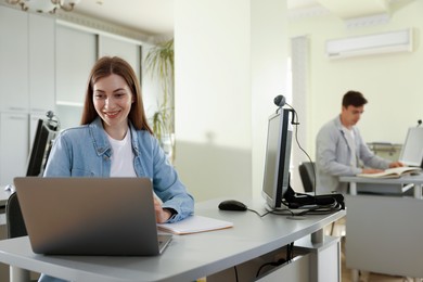 Photo of People working at desks in library, selective focus
