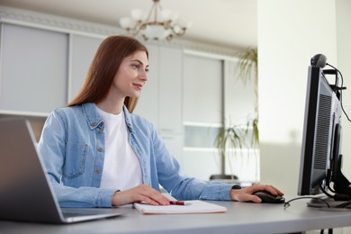 Photo of Woman working on computer at desk in public library