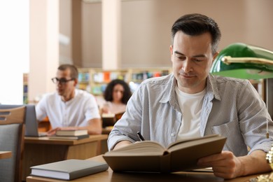 Photo of People studying at desks in public library, selective focus
