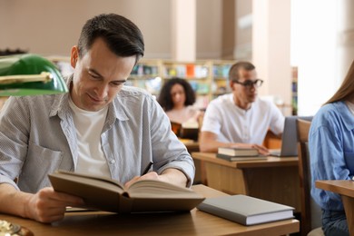 Photo of People studying at desks in public library, selective focus