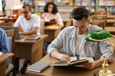 Photo of People studying at desks in public library, selective focus