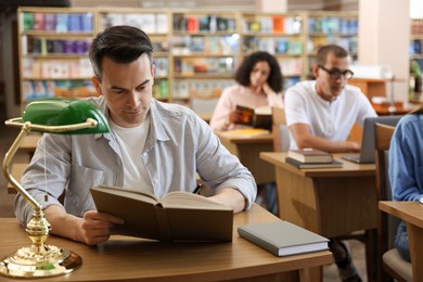 Photo of People studying at desks in public library, selective focus
