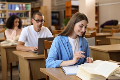 Photo of People studying at desks in public library, selective focus