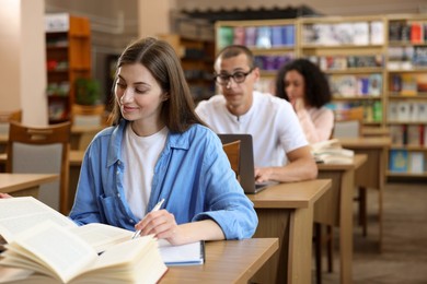 Photo of People studying at desks in public library, selective focus