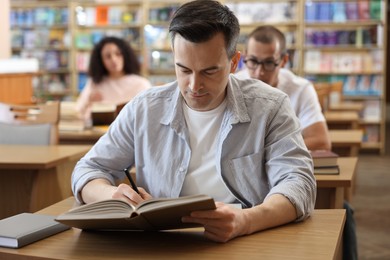 Photo of People studying at desks in public library, selective focus