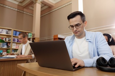 Photo of People studying at desks in public library, selective focus