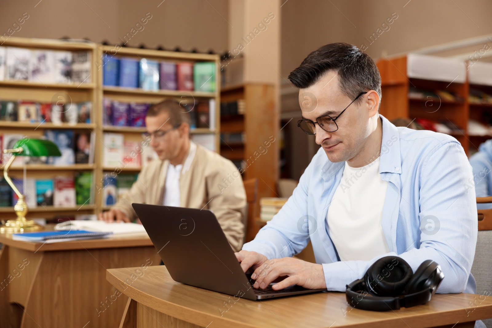 People studying at desks in public library, selective focus Photo of People studying at desks in public library, selective focus
