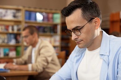 Photo of People studying in public library, selective focus