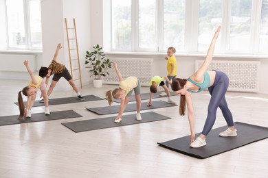 Photo of Group of children practicing yoga with coach on mats in class