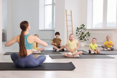 Photo of Group of children practicing yoga with coach on mats in class