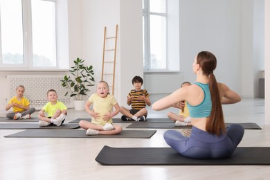 Photo of Group of children practicing yoga with coach on mats in class