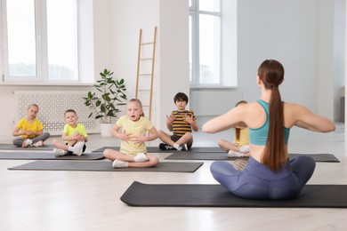 Photo of Group of children practicing yoga with coach on mats in class