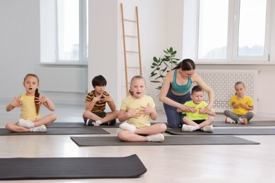 Photo of Yoga coach helping boy during group lesson indoors