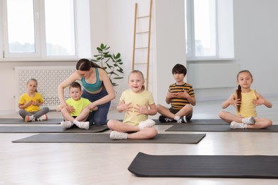 Photo of Yoga coach helping boy during group lesson indoors