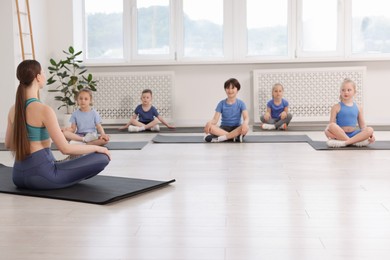 Photo of Group of children practicing yoga with coach on mats in class